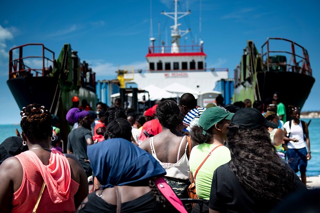 أشخاص يستقلون سفينة شحن لإجلاءها إلى ناسو في الميناء بعد إعصار دوريان